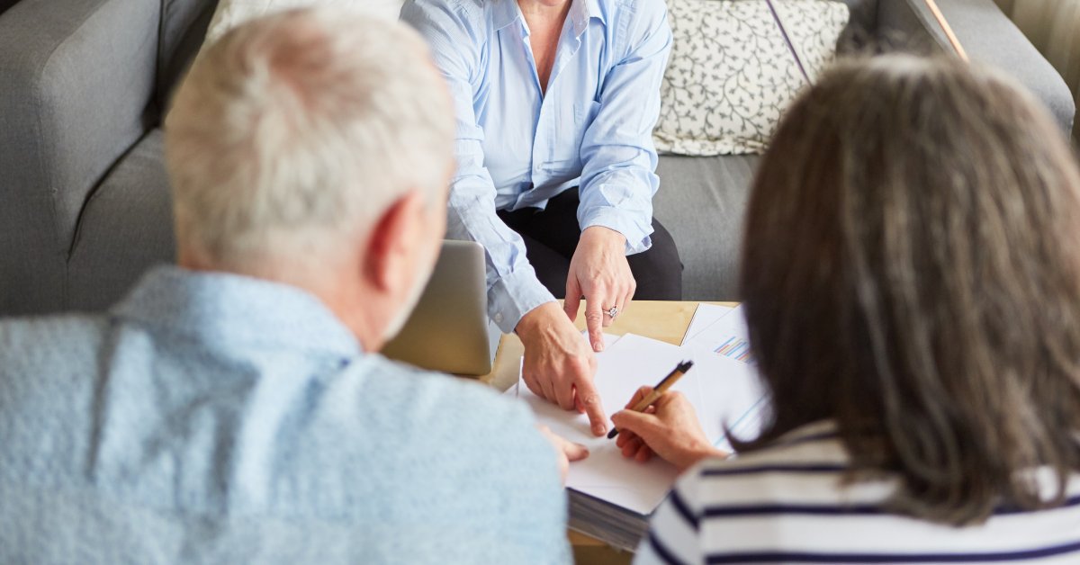 A tax specialist from a tax service bureau walking two seniors through their annual tax returns in a nicely decorated office.