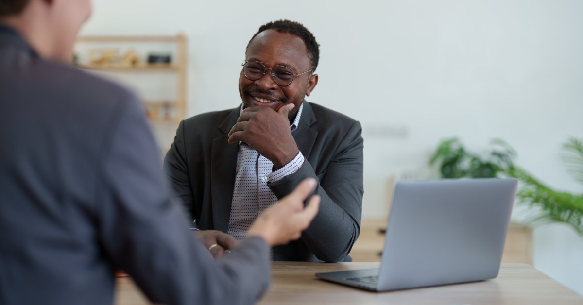 A tax professional meeting with a client. The two discuss finances with smiles on their faces and a laptop on the table.